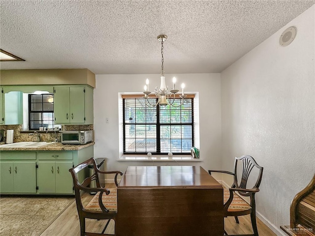 dining space with a notable chandelier, baseboards, plenty of natural light, and light wood-type flooring