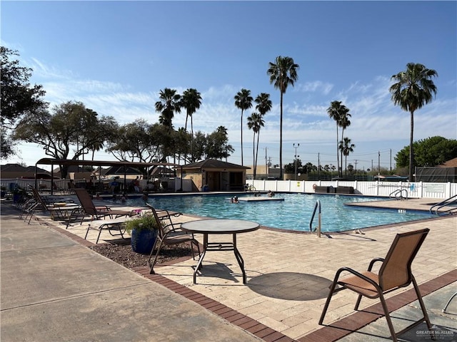 pool with a patio and fence