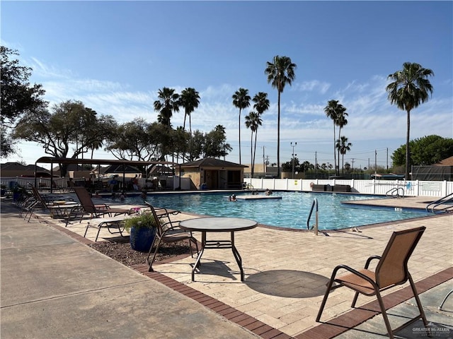 pool with a patio area and fence