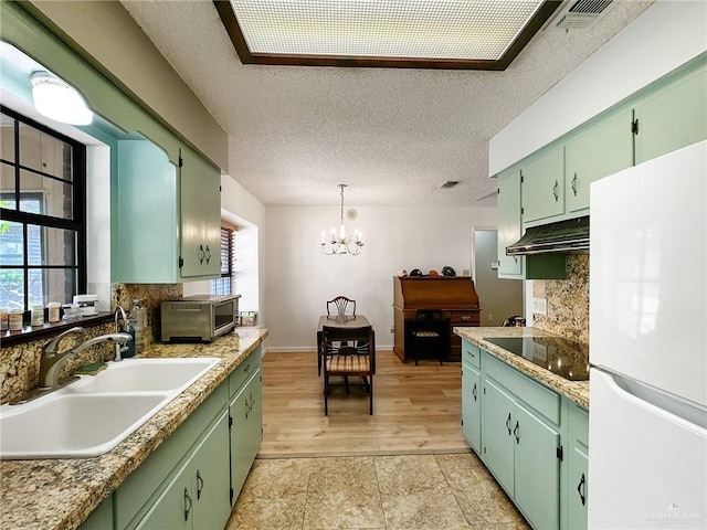 kitchen with freestanding refrigerator, a sink, under cabinet range hood, black electric stovetop, and tasteful backsplash