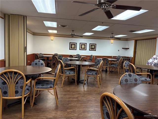 dining area with wood finished floors, visible vents, a drop ceiling, ceiling fan, and wainscoting