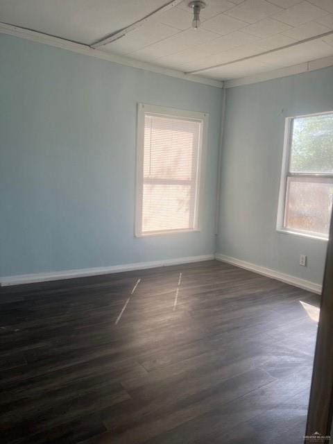 unfurnished room with baseboards, dark wood-style flooring, and crown molding