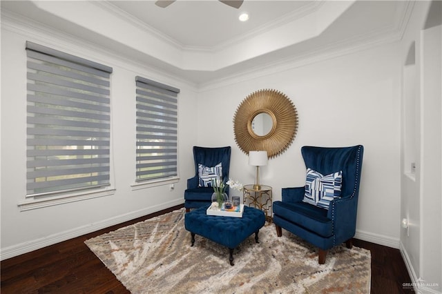 living area featuring a raised ceiling, crown molding, ceiling fan, and dark wood-type flooring