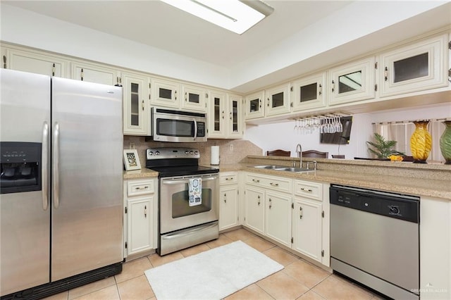 kitchen with cream cabinets, light tile patterned floors, and appliances with stainless steel finishes