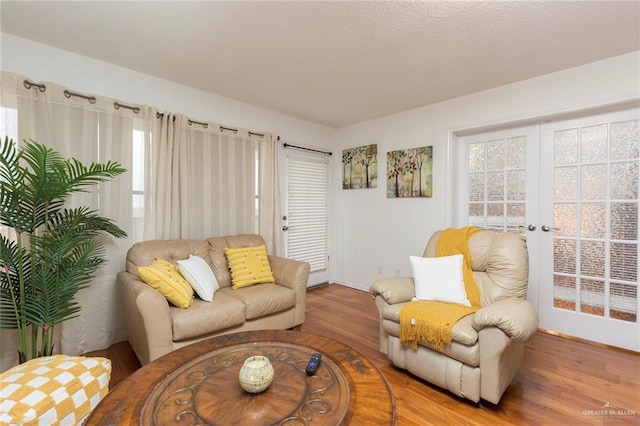 living room with plenty of natural light, hardwood / wood-style floors, and french doors