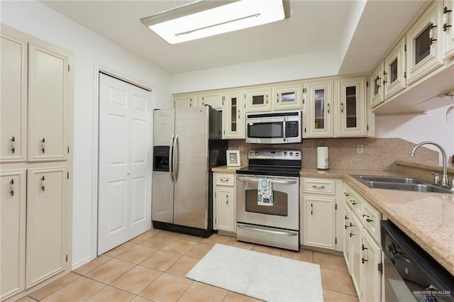 kitchen featuring sink, light tile patterned floors, cream cabinets, and appliances with stainless steel finishes