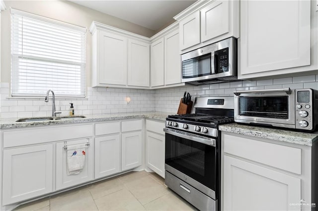 6327 Cascada Bend Rd, Mcallen, TX 78504 - kitchen featuring stainless steel appliances, light tile patterned floors, white cabinetry, backsplash, and light stone countertops