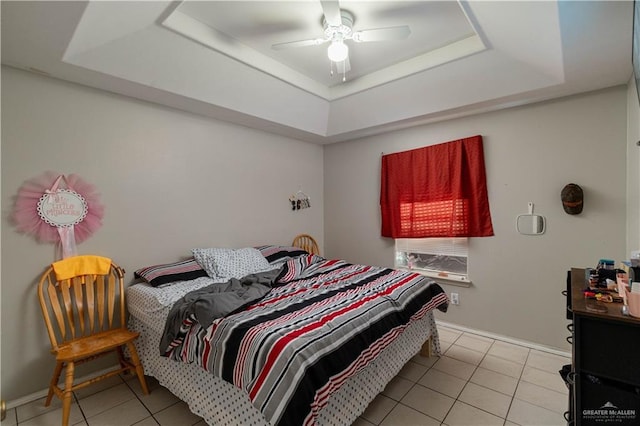 bedroom featuring ceiling fan, a raised ceiling, and light tile patterned flooring