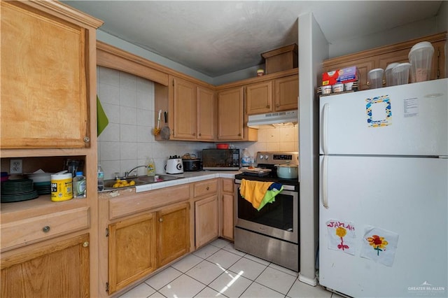 kitchen featuring stainless steel range with electric cooktop, white refrigerator, sink, backsplash, and light tile patterned flooring