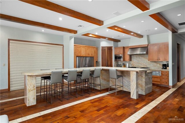 4616 Gulf Blvd S, Unit South, South Padre Island, TX 78597 - kitchen with stainless steel appliances, wall chimney exhaust hood, decorative backsplash, beamed ceiling, and dark wood-style floors