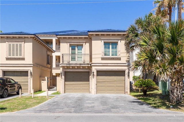 4616 Gulf Blvd S, Unit South, South Padre Island, TX 78597 - view of front of house with stucco siding, a garage, asphalt driveway, and a balcony