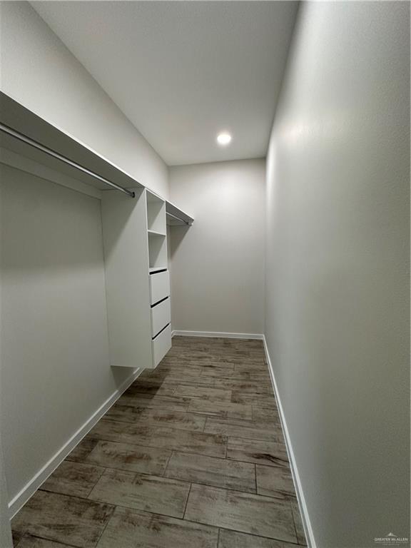 walk in closet with dark hardwood / wood-style flooring