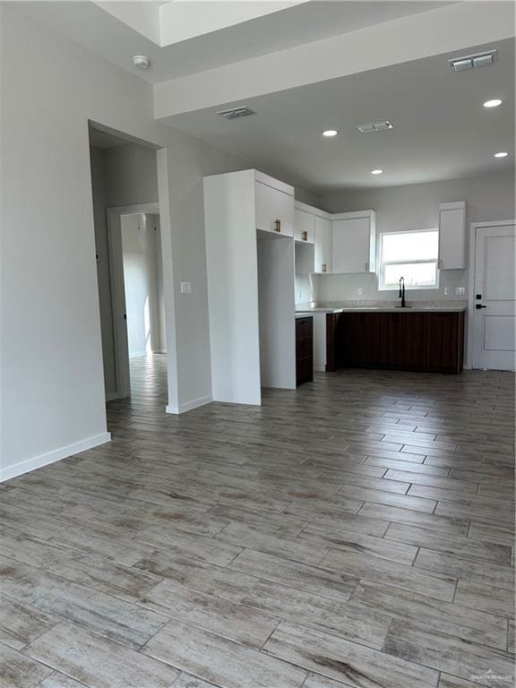 kitchen with sink, dark brown cabinets, light hardwood / wood-style flooring, and white cabinets