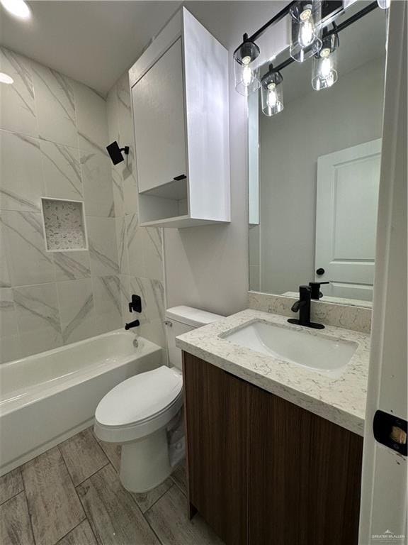 full bathroom featuring vanity, tiled shower / bath combo, and toilet