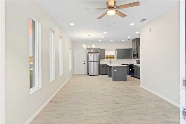 kitchen with visible vents, gray cabinets, a center island, stainless steel appliances, and light countertops