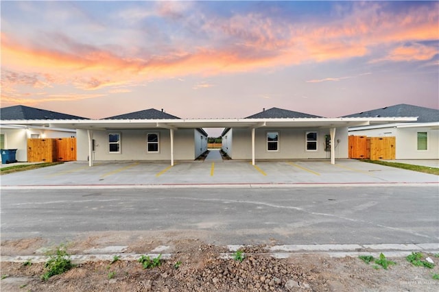 ranch-style house with a carport, stucco siding, and fence