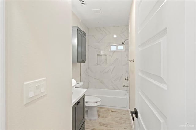 full bath featuring visible vents, toilet, wood finished floors, shower / washtub combination, and vanity