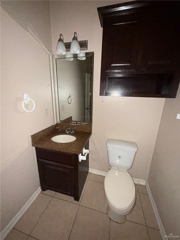 bathroom with toilet, vanity, and tile patterned floors