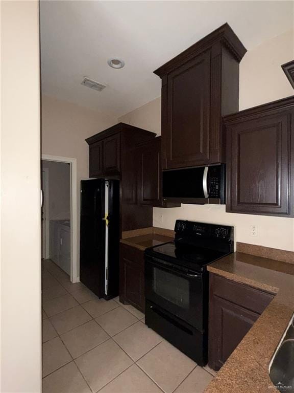 kitchen with dark brown cabinetry, light tile patterned floors, and black appliances