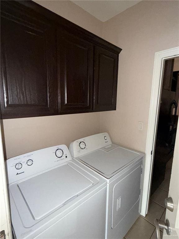 laundry area featuring cabinets, light tile patterned floors, and washer and clothes dryer