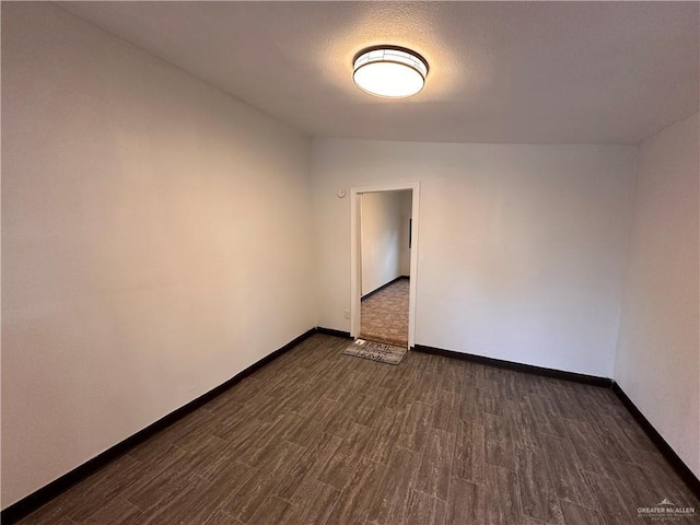 unfurnished room featuring lofted ceiling, dark wood-style flooring, and baseboards