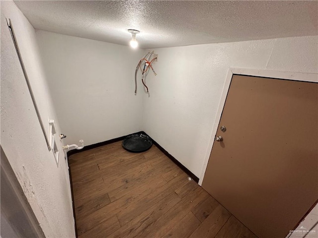 unfurnished room with a textured ceiling, baseboards, and wood finished floors