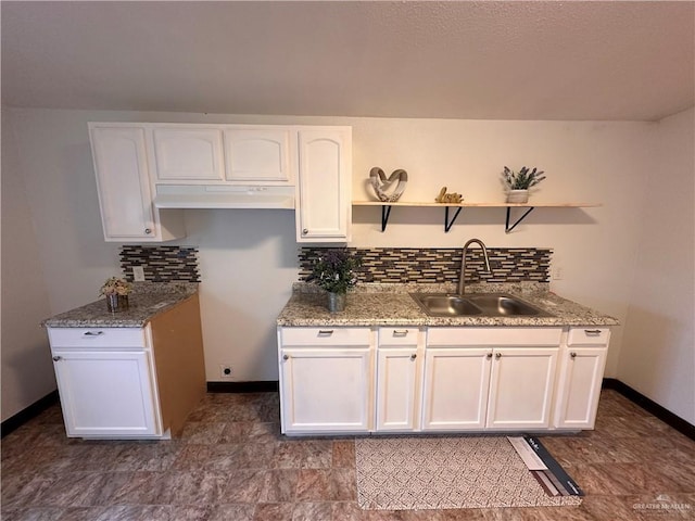 kitchen featuring open shelves, decorative backsplash, white cabinets, a sink, and under cabinet range hood