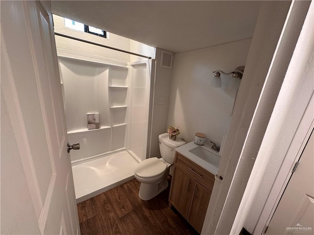 bathroom with toilet, wood finished floors, vanity, visible vents, and walk in shower