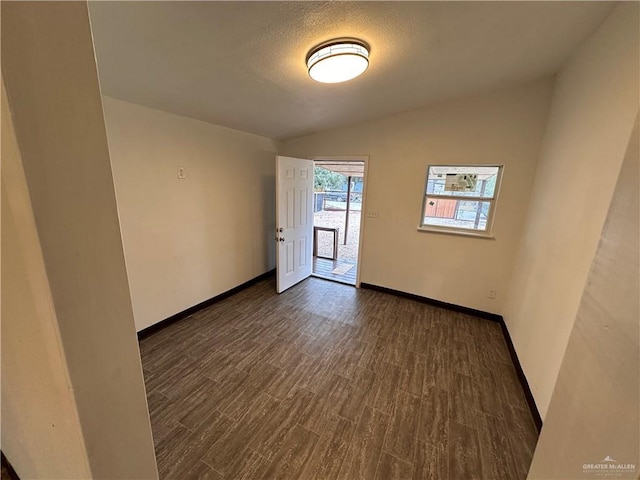 spare room featuring a textured ceiling, baseboards, vaulted ceiling, and dark wood-type flooring