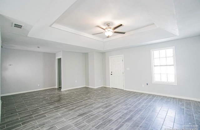 unfurnished room featuring hardwood / wood-style floors, a tray ceiling, and ceiling fan