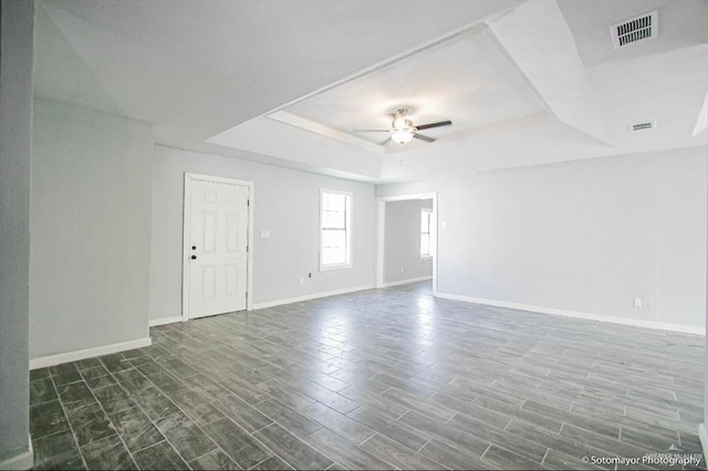 spare room featuring dark hardwood / wood-style flooring, a tray ceiling, and ceiling fan