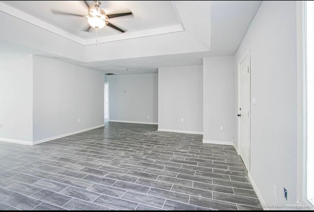 spare room featuring dark hardwood / wood-style flooring, a tray ceiling, and ceiling fan