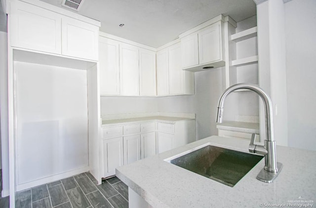 kitchen with white cabinets, light stone countertops, and sink