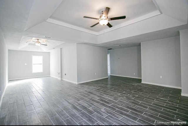 unfurnished room featuring dark hardwood / wood-style floors, ceiling fan, and a tray ceiling