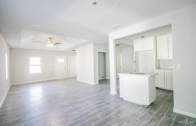 kitchen with white cabinetry, sink, ceiling fan, hardwood / wood-style floors, and an island with sink