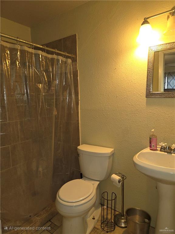 full bath featuring tile patterned flooring, toilet, and tiled shower