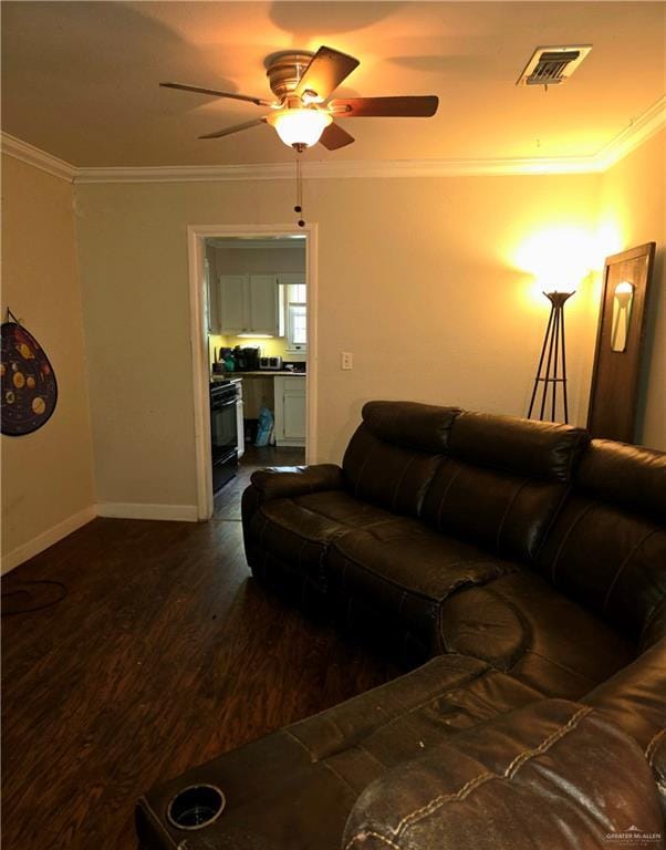 living area with visible vents, ornamental molding, baseboards, dark wood-style floors, and a ceiling fan
