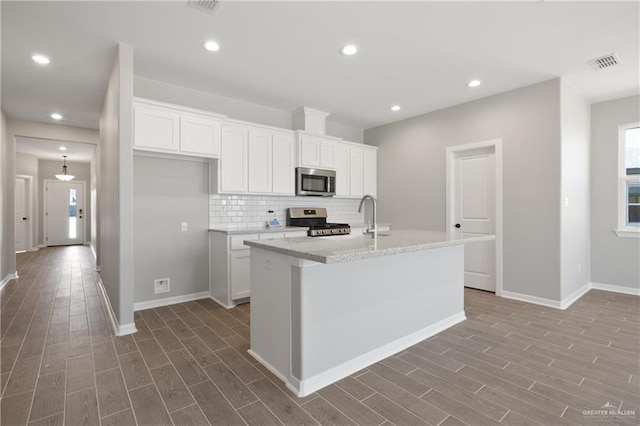 kitchen featuring baseboards, appliances with stainless steel finishes, wood finished floors, and visible vents