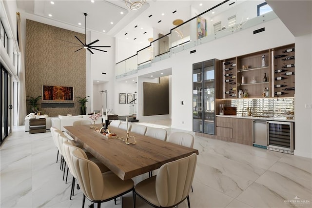 dining space featuring a high ceiling, beverage cooler, and ceiling fan