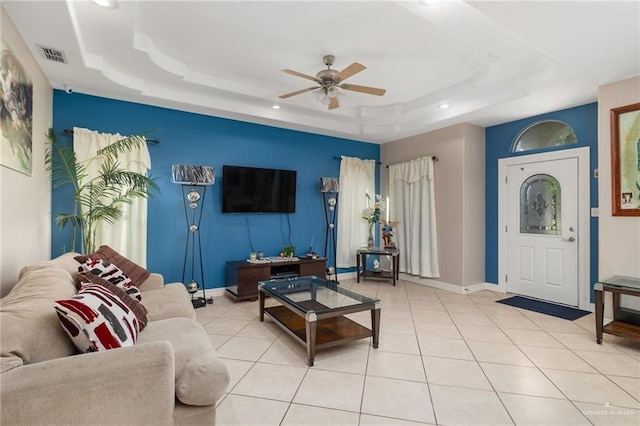 tiled living room with a raised ceiling and ceiling fan