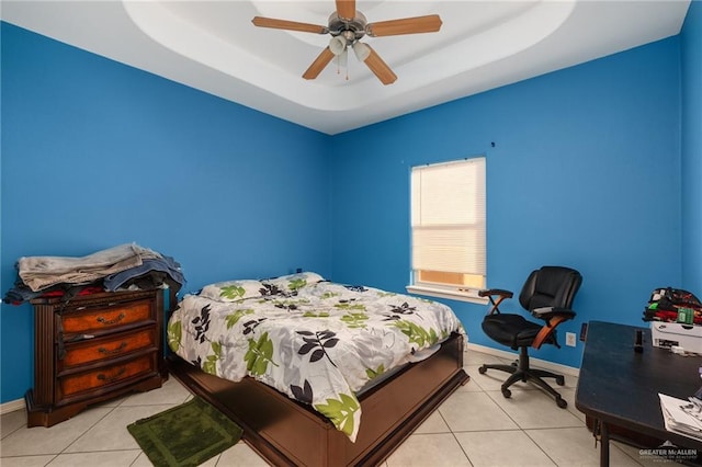 tiled bedroom featuring ceiling fan and a tray ceiling