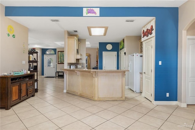 kitchen featuring a breakfast bar, white refrigerator, and light tile patterned floors