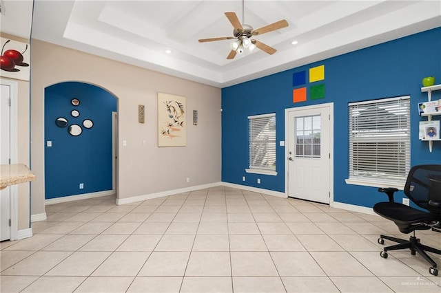 tiled office space featuring a raised ceiling and ceiling fan