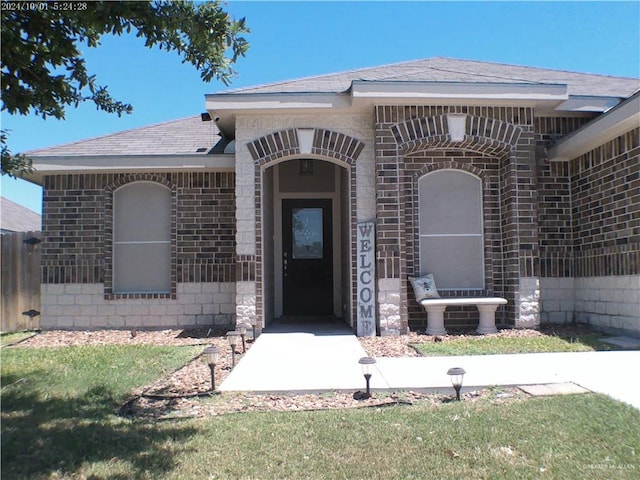 7612 N 40th St, Mcallen, TX 78504 - property entrance featuring brick siding, a shingled roof, and a lawn