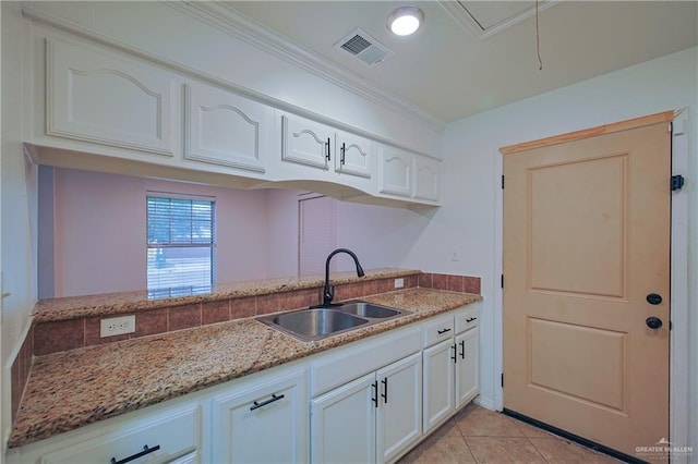 kitchen with light stone countertops, white cabinetry, light tile patterned flooring, and sink