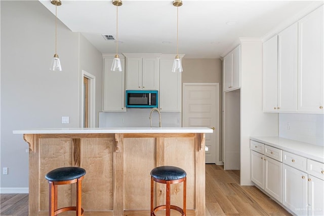 6608 Primavera St, Pharr, TX 78577 - kitchen featuring light wood-type flooring, decorative backsplash, a kitchen breakfast bar, and white cabinetry