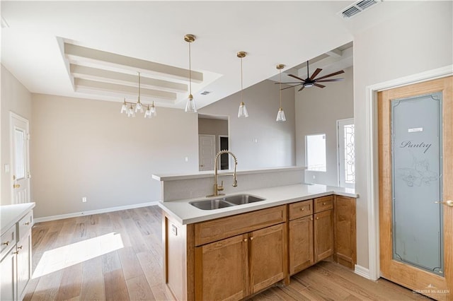 6608 Primavera St, Pharr, TX 78577 - kitchen with a sink, a tray ceiling, light wood-style floors, a peninsula, and decorative light fixtures