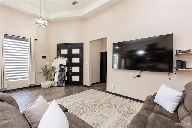 living room with dark hardwood / wood-style floors and a raised ceiling