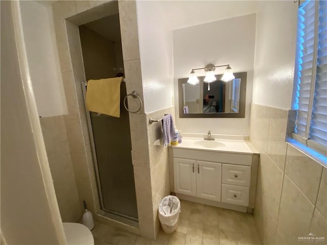 1005 Bryce Dr, Mission, TX 78572 - bathroom featuring tile walls, a shower stall, vanity, toilet, and wainscoting