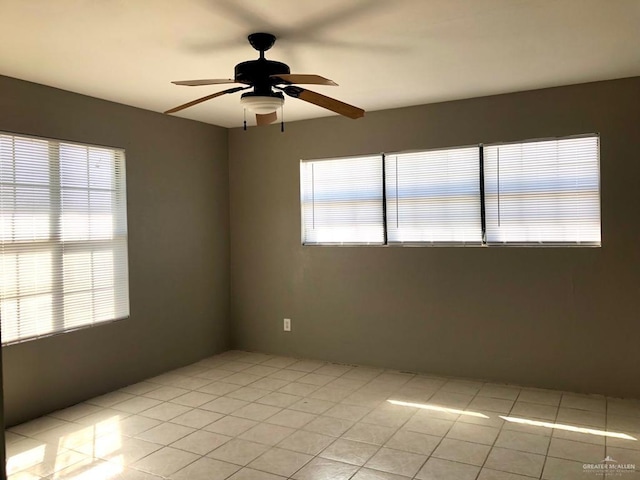 tiled spare room with ceiling fan and a healthy amount of sunlight